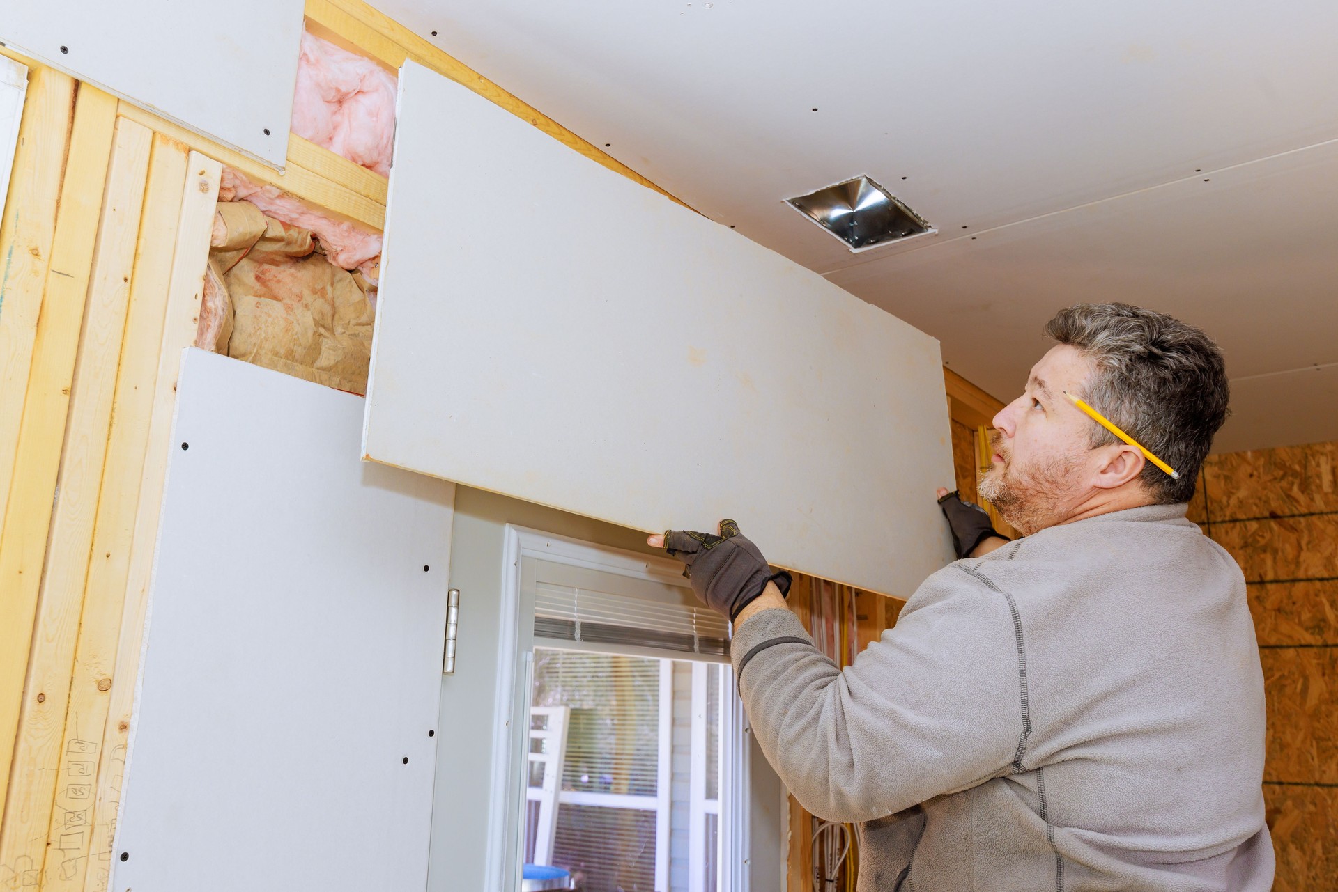 Man installing drywall in a residential room during home renovation project